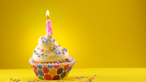 birthday decorated cupcake with a candle and sprinkles. the candle will be blown out at the end.  - sliding shot