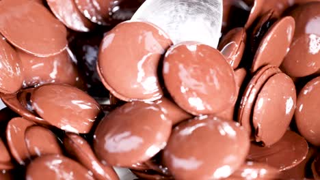 spoon stirring glossy chocolate discs in motion