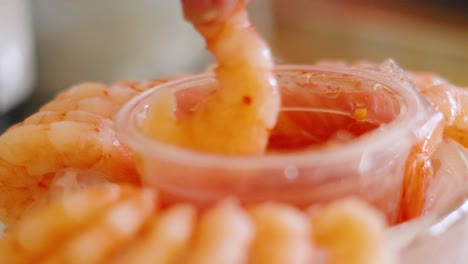 hand dipping seafood prawn shrimp into thai sweet chilli dipping sauce to eat at festive party gathering during holidays season 4k