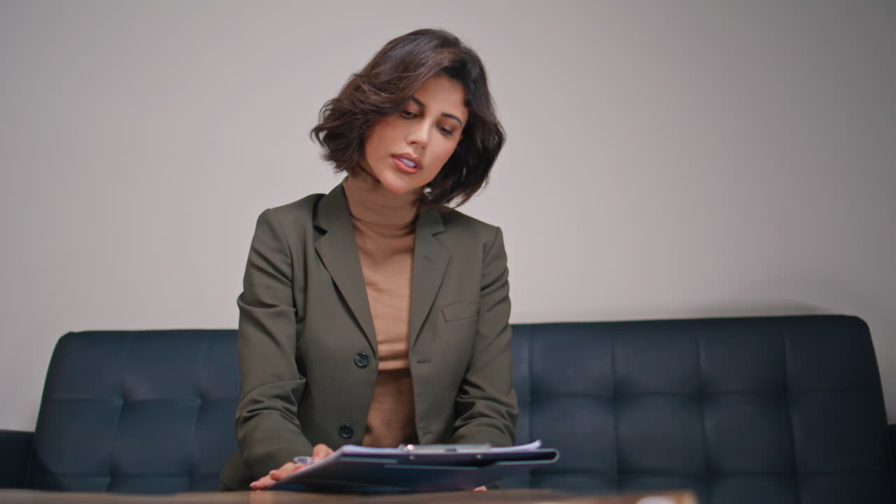 Elegant lady evaluating documents on clipboard sitting office couch closeup