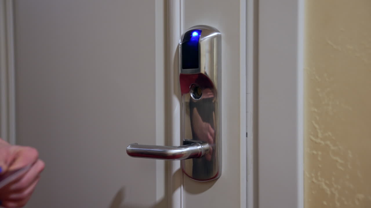 Hotel door with digital lock. Female hand puts the keycard to the electronic sensor and then opens the door.