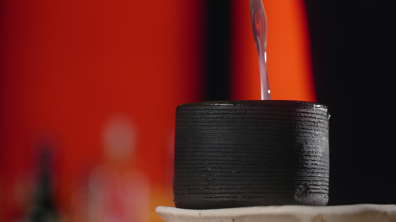 Pouring Liquid into a Dark Cup