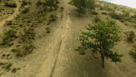 moto racer rides along dirt road uphill fpv. rider maneuvers vehicle on wild offroad land at motocross racing. enjoying of speed and motion