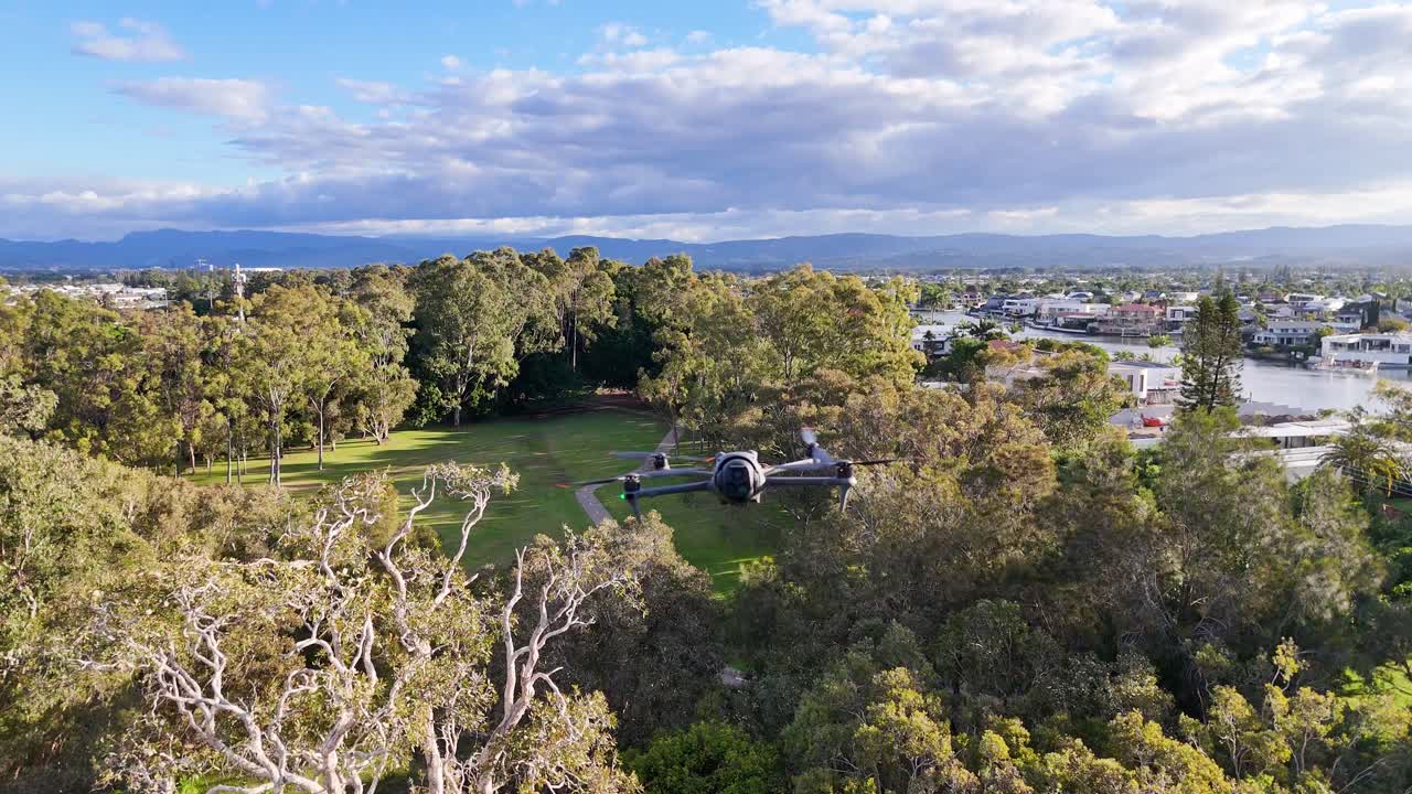 Drone captures scenic park and urban landscape in Gold Coast, Australia, under soft daylight with lush greenery and distant buildings