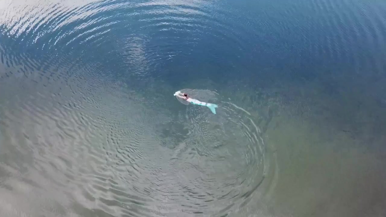 Mermaid swimming with an underwater scooter in a lake.