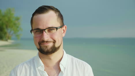 Portrait-Of-A-Young-Man-On-A-Tropical-Beach-In-An-Easy-Shirt-He-Smiles-And-Looks-Into-The-Camera-Wea