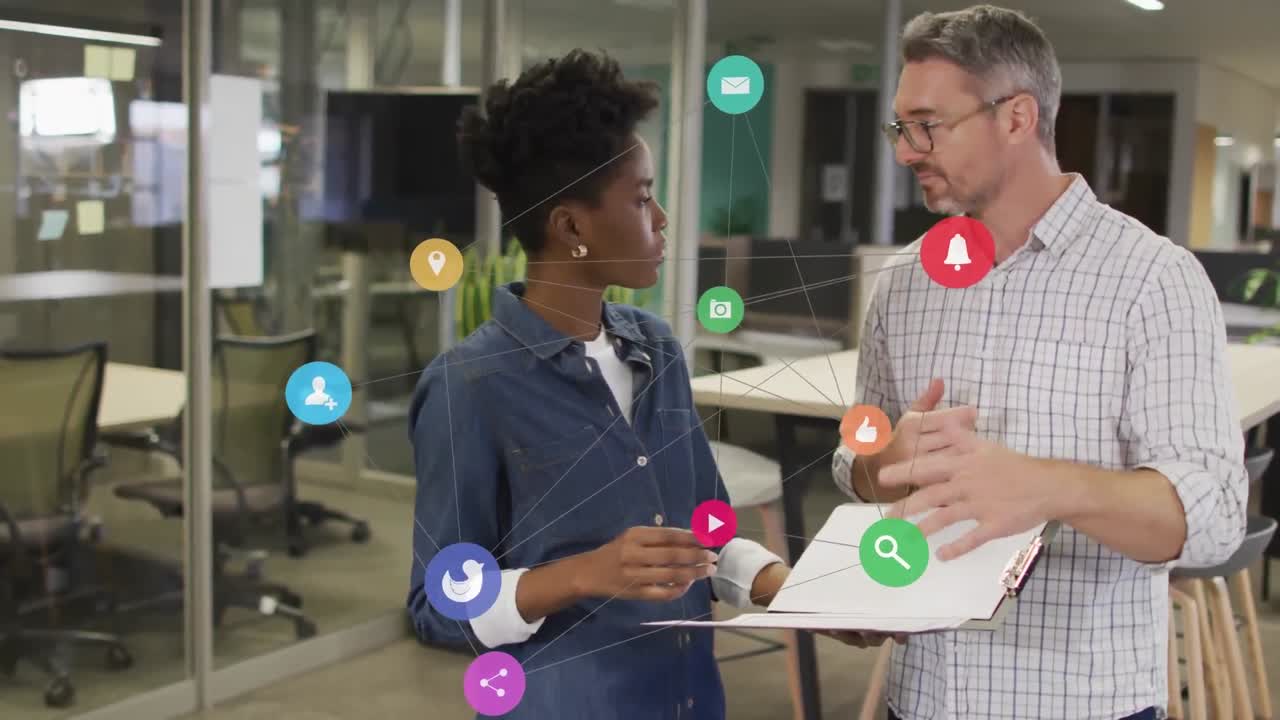 Animation of connected icons over diverse coworkers discussing reports in office