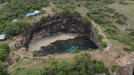 Tourists-walking-along-the-walkway-around-a-cove-in-the-coast-of-Broken-Beach,-Nusa-Penida,-Bali,-Indonesia