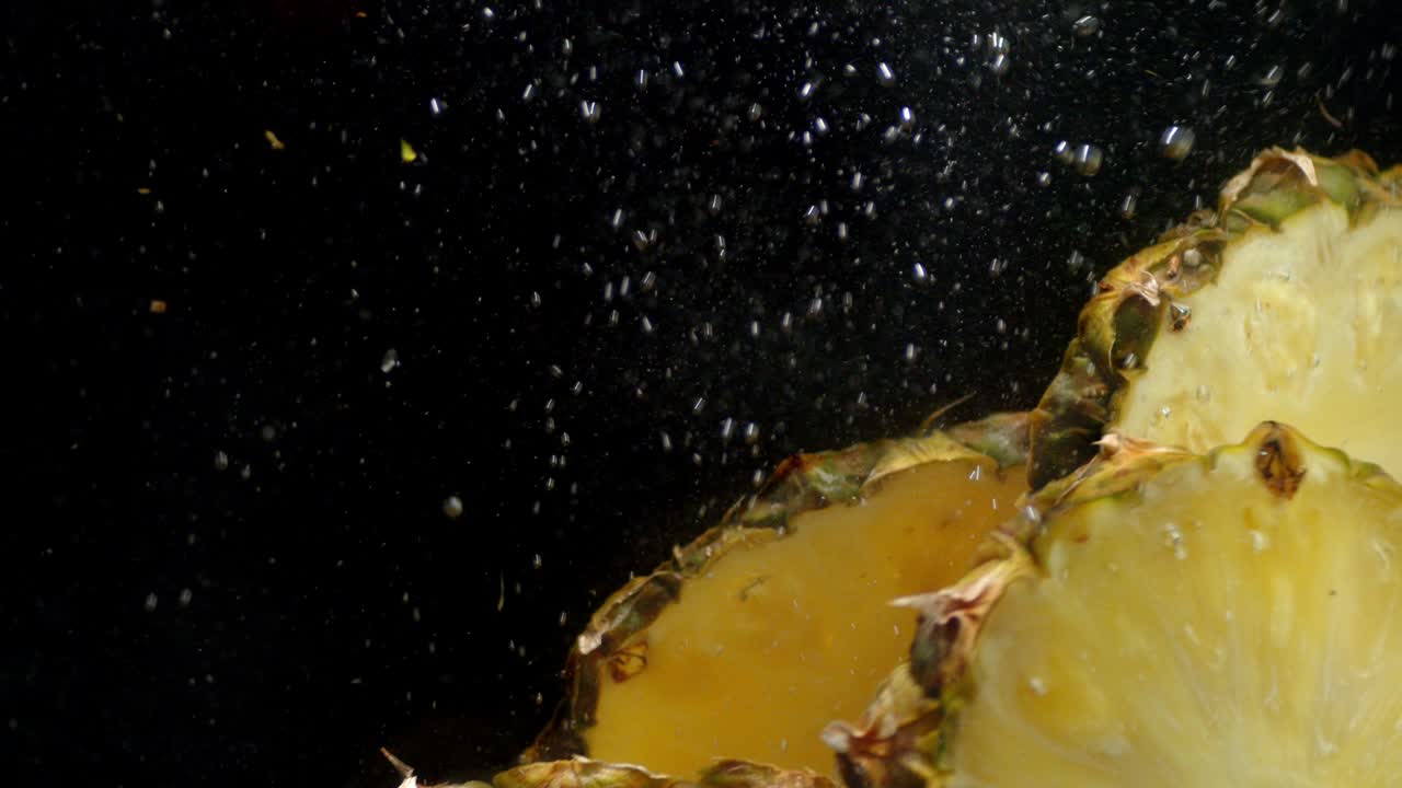 pedazos de piña cayendo bajo el agua con burbujas de aire.