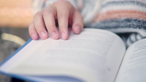 primer plano de los dedos y la mano de la persona siguiendo las líneas que leyeron en un libro