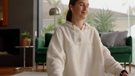 meditating at home, woman wearing earphones and hoodie, enjoying relaxation time