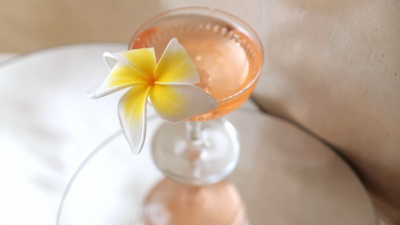 Pretty peach cocktail with a frangipani blossom