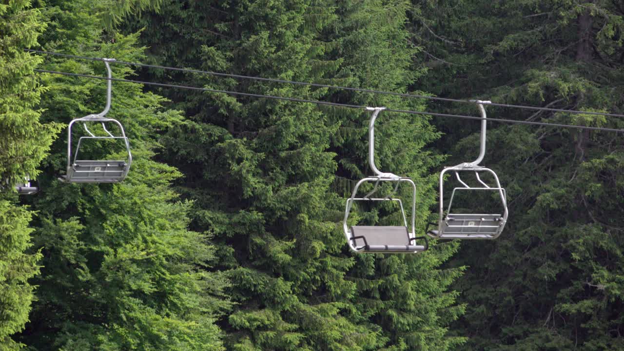 Le sedie di una seggiovia attraversano una radura nel bosco in una bella e soleggiata giornata estiva