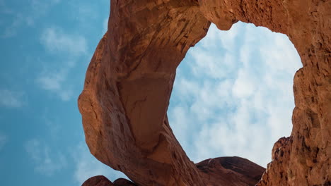 vertical 4k time lapse, clouds moving above natural arch and red sandstone rock formations