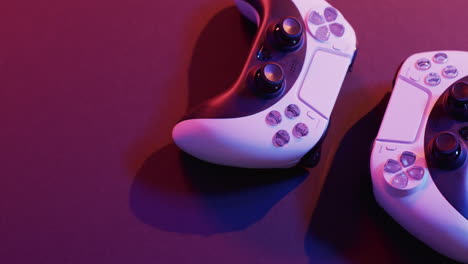 video of close up of video game pad controllers with copy space on neon background