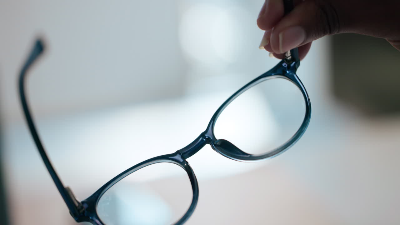 A pair of blue eyeglasses being held up