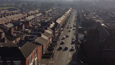 aerial rising view establishing rows of victorian terraced houses with a long road leading towards the bustling town centre at sunrise