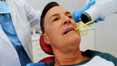 Dentist-examining-a-male-patient-with-tool