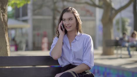 mujer caucásica en el parque hablando bonita por teléfono, sonriendo