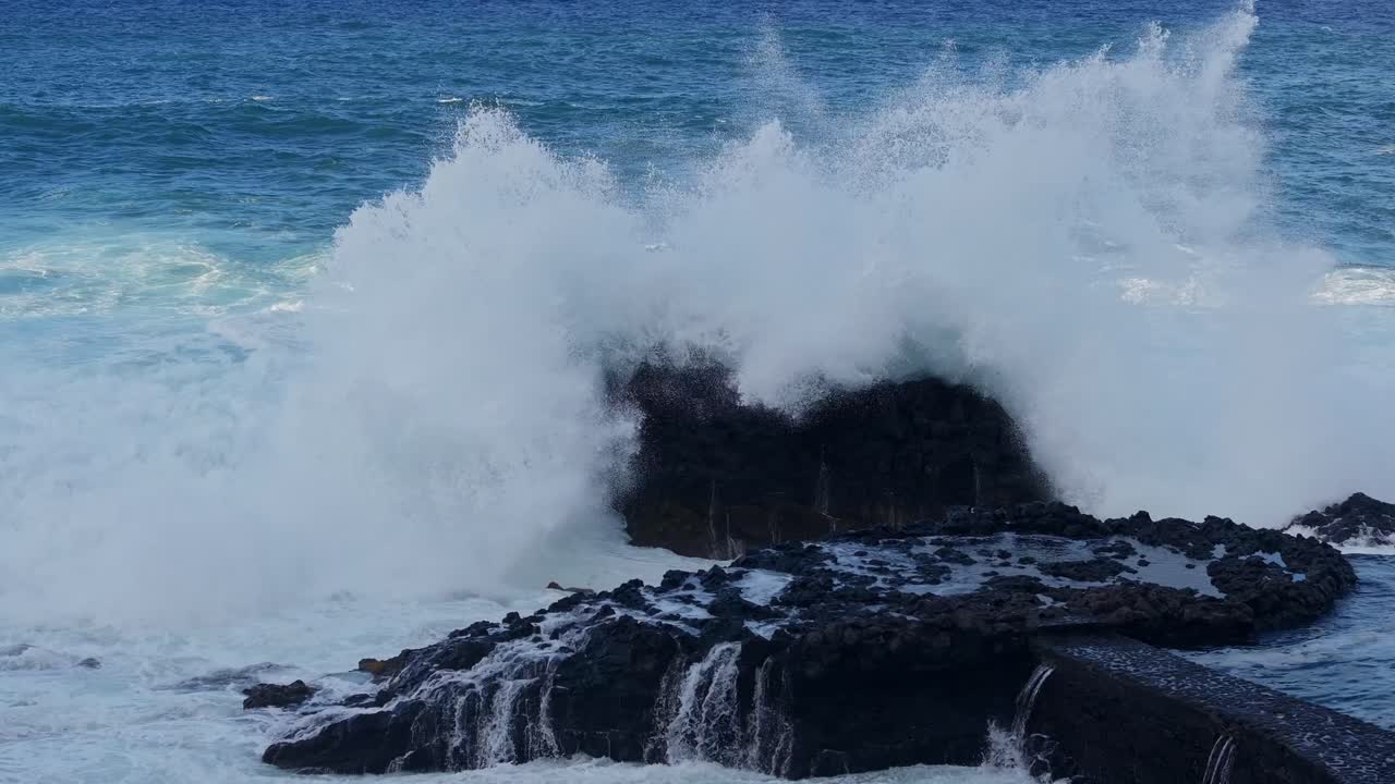 Foamy waves pound volcanic rocks on remote Canary shoreline with intense force