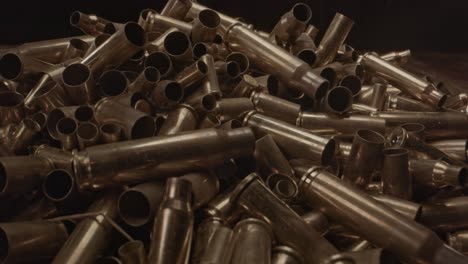 extreme close zoom in of large pile of bullet cases on a wooden surface