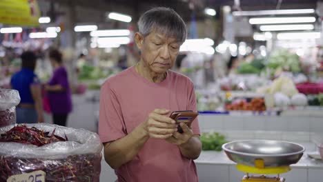 senior man using phone in a market