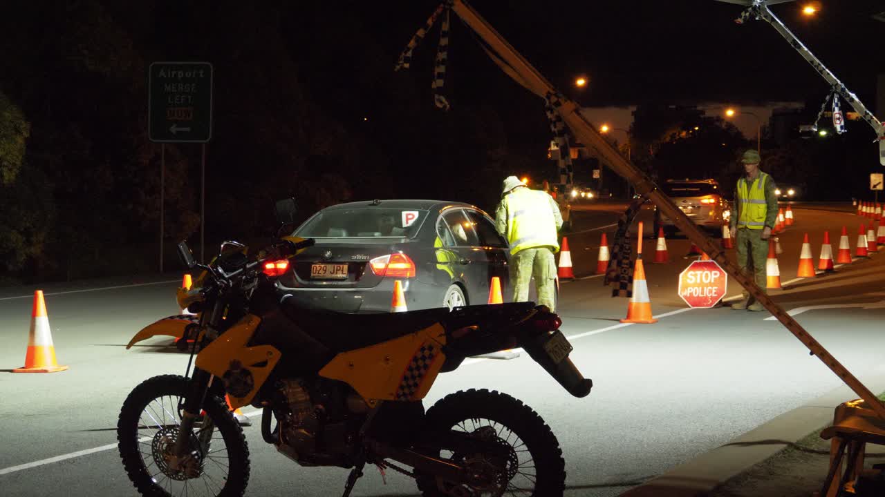 Motorbike Parked On The Roadside - Military Checking The Border Declaration Of A Black Car - Cars From NSW Crossing The Border At Gold Coast, QLD, Australia At Night. - wide shot