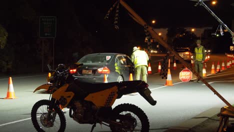 motorbike parked on the roadside - military checking the border declaration of a black car - cars from nsw crossing the border at gold coast, qld, australia at night. - wide shot