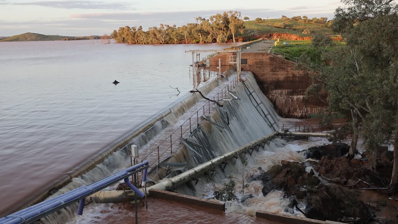 aguas de inundación que fluyen poderosamente sobre la pared de una presa en el interior remoto, normalmente seco, de australia