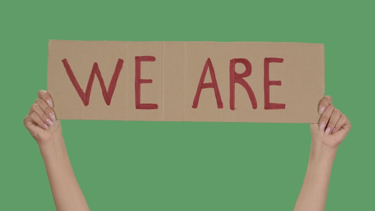 cartel de protesta con la inscripción somos. fondo para ilustrar el movimiento por la libertad de los derechos humanos. manos femeninas sosteniendo cartel pantalla verde, llave de croma. primer plano. cámara lenta
