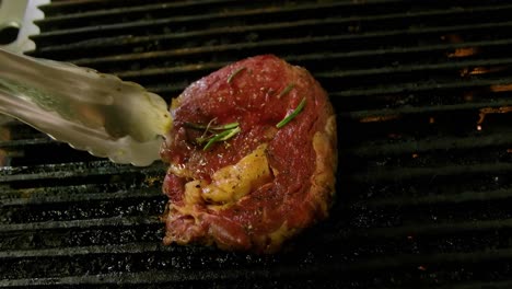 grill master flips steak showcasing beautiful grill marks cooking over propane gas flame