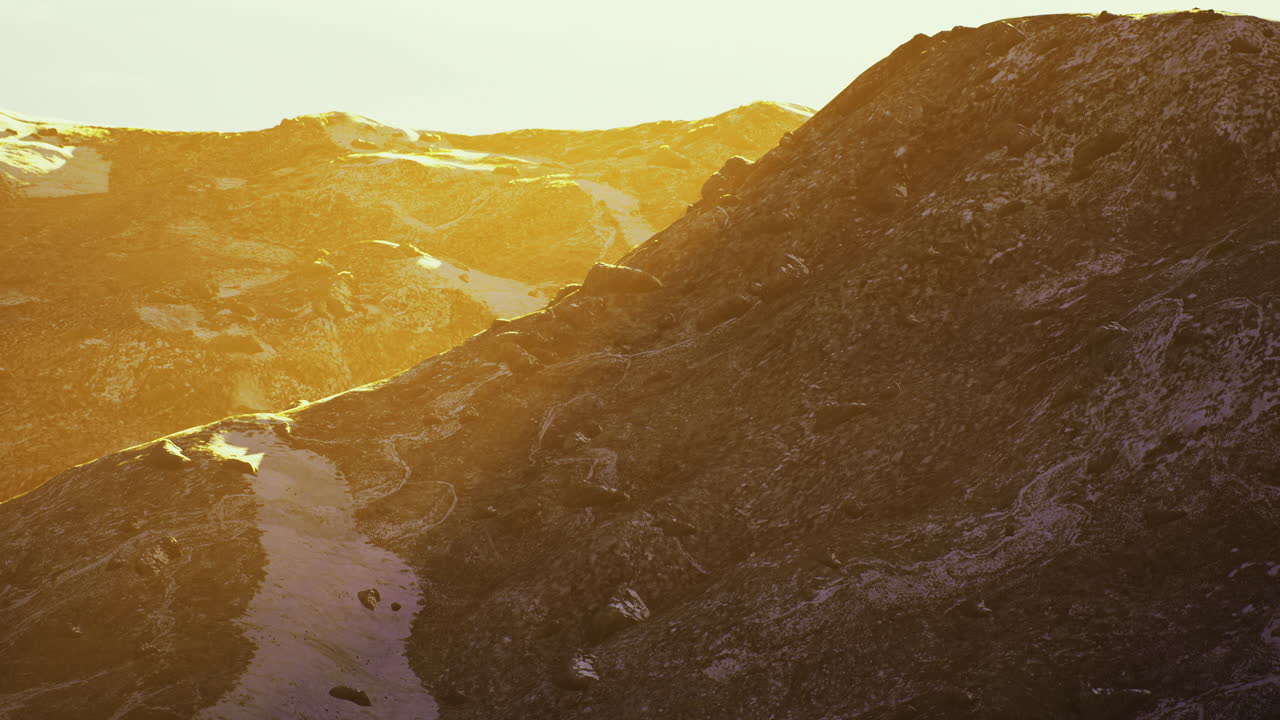 Golden sunlight illuminating rocky mountain landscape at sunset