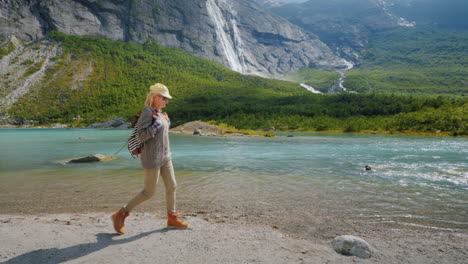 a tourist woman walks alone surrounded by majestic nature - mountains with waterfalls on top the tra