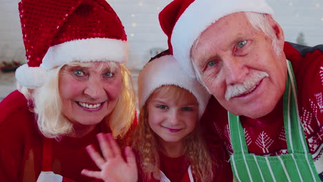 POV-of-senior-grandparents-with-grandchild-girl-taking-selfie-on-mobile-phone-on-Christmas-kitchen