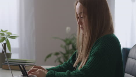 adult-woman-is-working-with-laptop-in-apartment-at-weekend-using-laptop-with-internet-connection-for-sending-message-medium-portrait-in-home-office