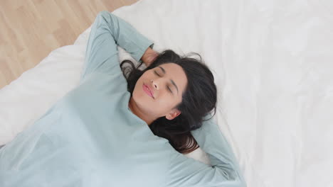 relaxing on bed, mature asian woman smiling with eyes closed, enjoying spa day, at home