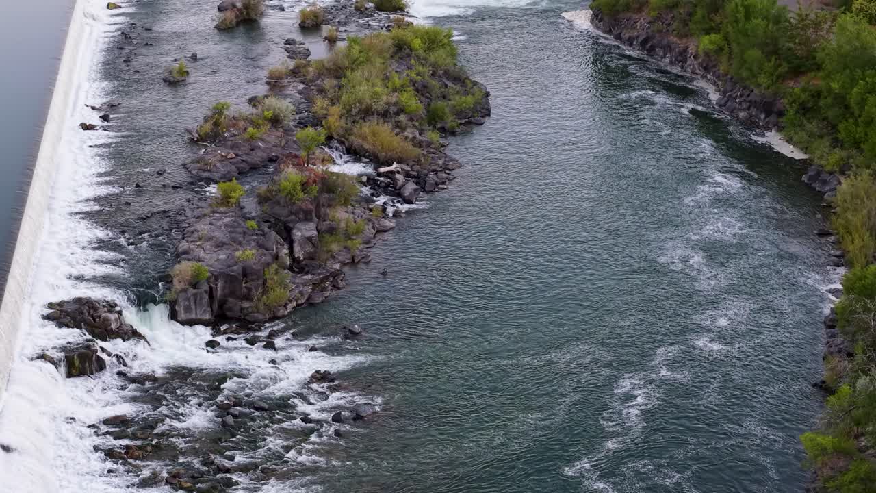 Widok z drona na rzekę Snake River przepływającą obok małych wysp i skalistych bystrzy z drzewami i terenami rolnymi