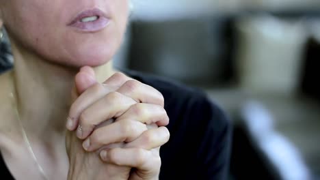 woman-praying-with-hand-over-her-face-on-grey-background-with-people-stock-video