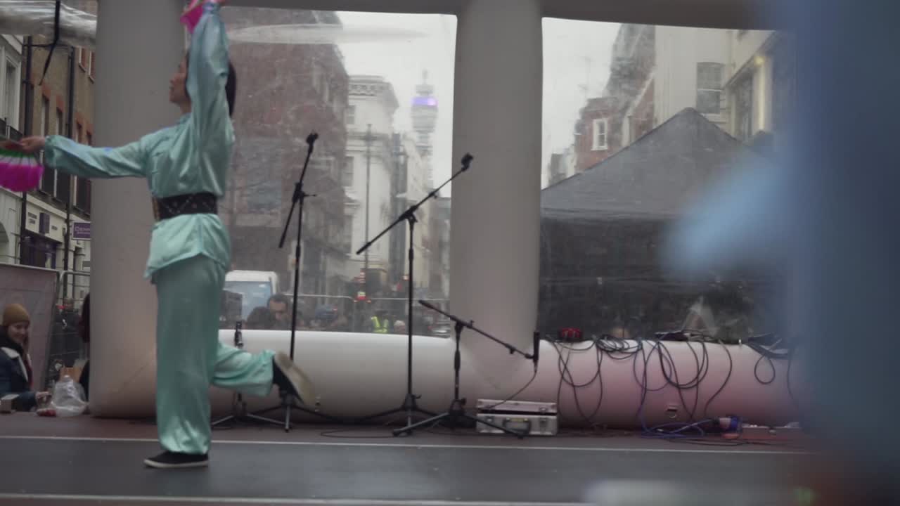 Adult chinese woman with typical costume performing dance over a stage in london city during new year celebration, england uk