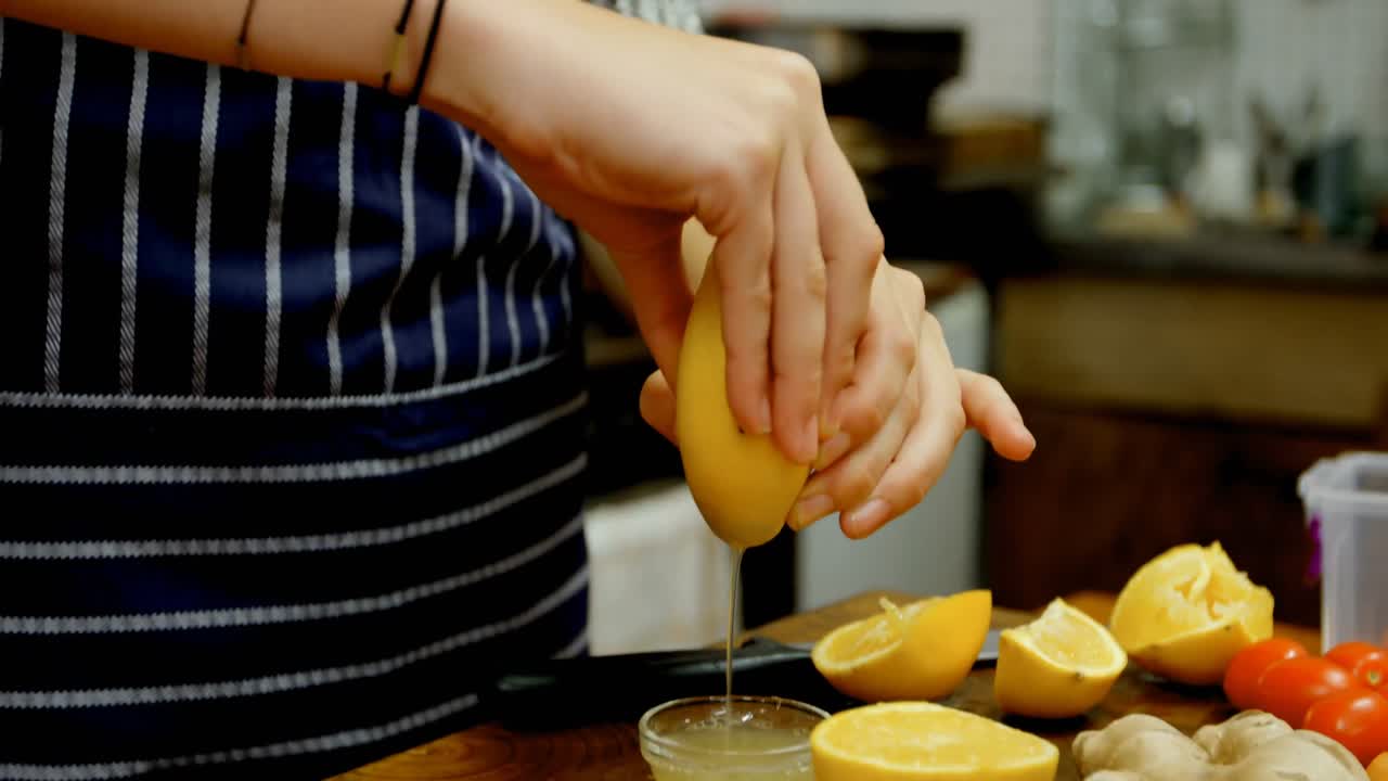 mujer exprimiendo limón en un plato en la cocina de la cafetería 4k