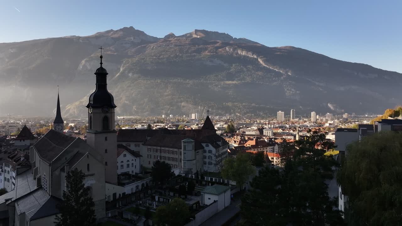 Elegant church spire rises over Chur’s rooftops against majestic Swiss Alpine mountains