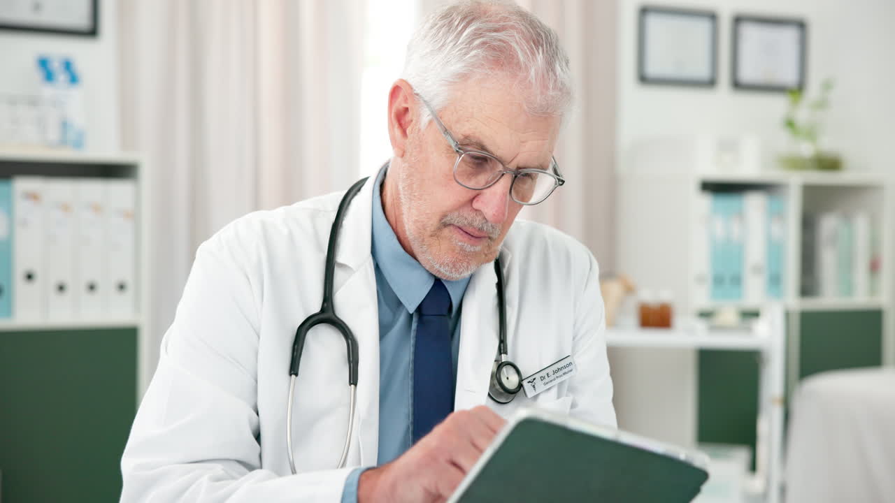 Médico sênior usando tablet digital em um consultório médico.