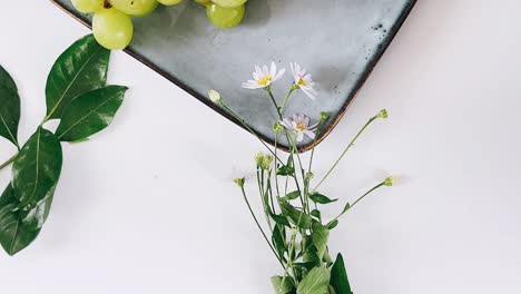 fresh grapes, flowers, and leaves on a plate