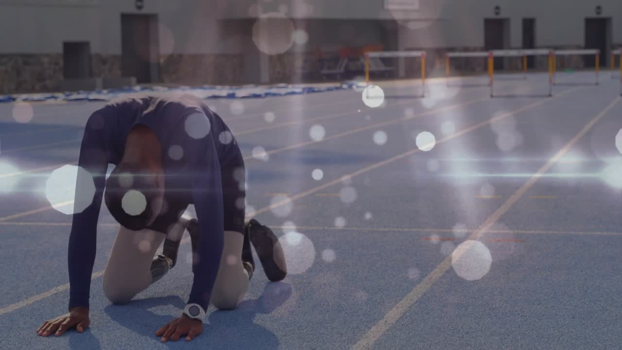 Atleta maschio adolescente che termina uno sprint su pista blu, si inginocchia asciugandosi la fronte, crollando e riprendendo fiato.