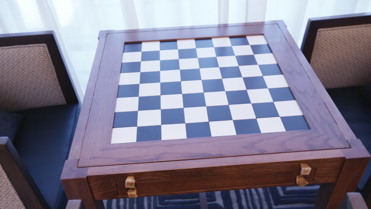 Vista de cima de uma mesa de xadrez de mogno feita sob medida integrada em uma sala comum de hotel de luxo, destacando as comodidades para os hóspedes