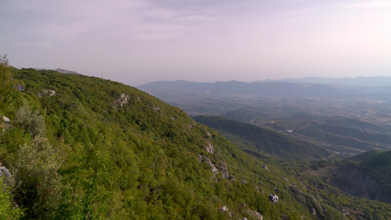dos góndolas que se cruzan por encima de las verdes montañas en un día despejado