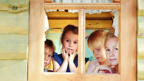 4人の女の子が家の窓の外を見る