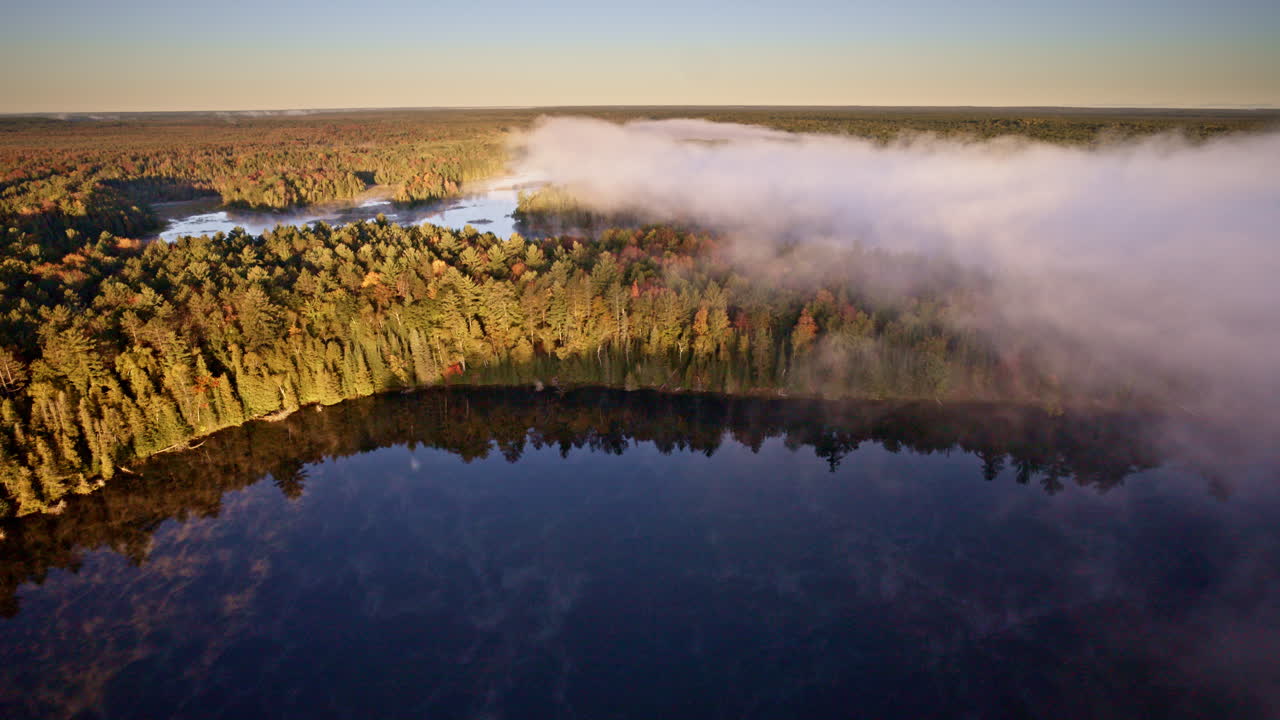 Cinematic drone view of mist drifting upward from the water at daybreak