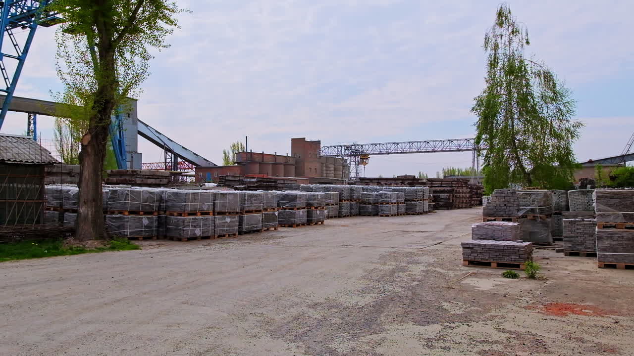Road leading to the construction site with building materials on both sides. Packs of new grey bricks covered with plastic.