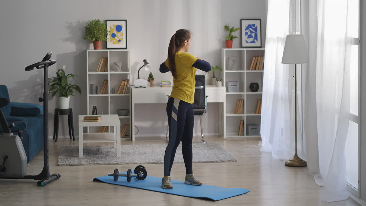 gimnasia para la columna vertebral la mujer está entrenando sola en casa el fin de semana de pie en una alfombra deportiva y moviendo las manos y el torso estilo de vida saludable